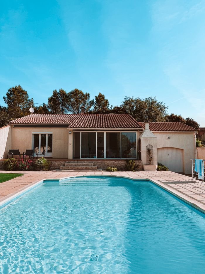 Charming suburban home with a swimming pool, set against a clear blue sky.