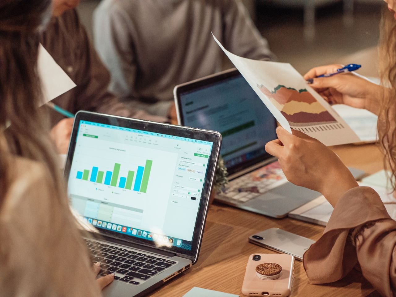 Crafting Captivating Headlines: Your awesome post title goes here A group engaged in a business meeting analyzing charts on laptops and papers.