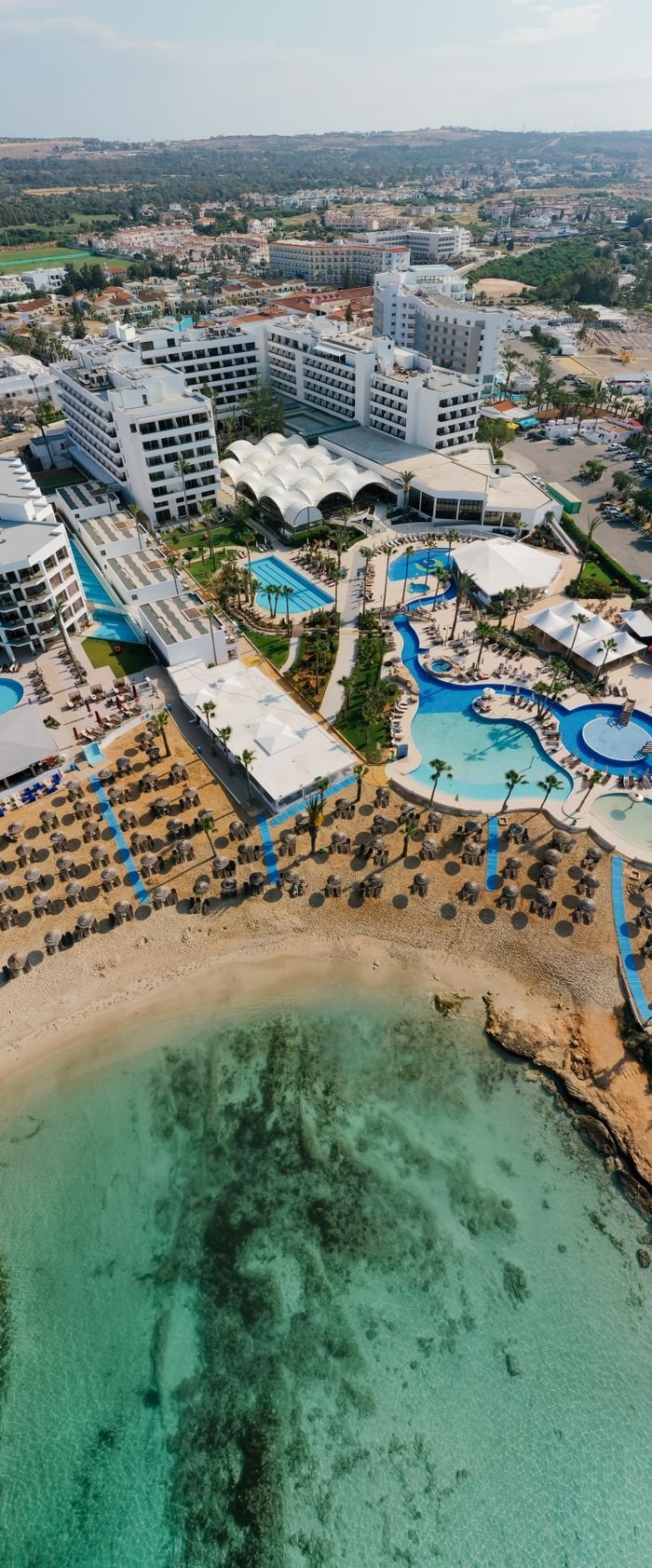 Stunning aerial shot of a beachfront resort in Cyprus, showcasing turquoise waters and modern amenities.